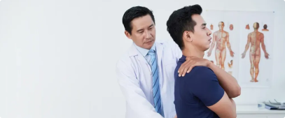 A doctor examines the neck of a male patient for neck pain in a clinic, with anatomical charts visible in the background.