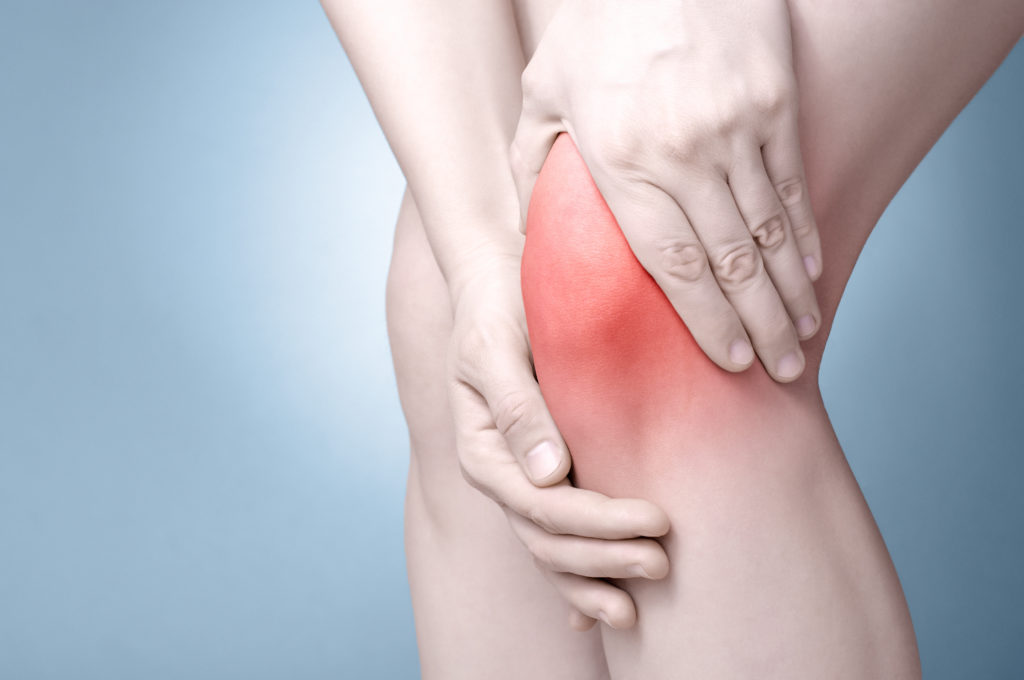 A person experiencing knee pain, holding their knee with both hands highlighted by a red painful area on a blue background, potentially considering regenerative therapy.