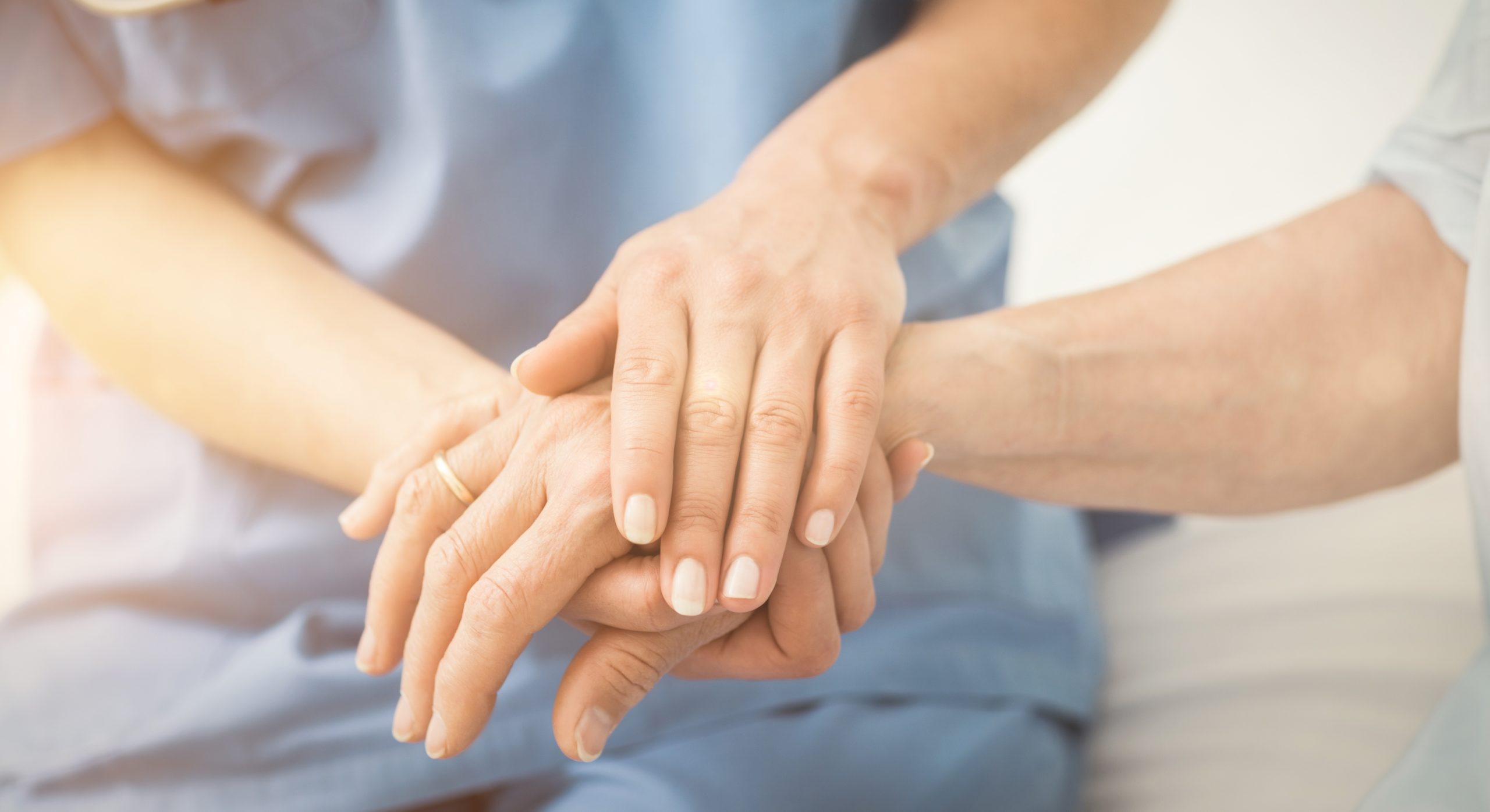Close-up of a nurse practitioner holding an elderly patient's hands in a comforting and caring manner, symbolizing support and compassion in managing auto injuries.