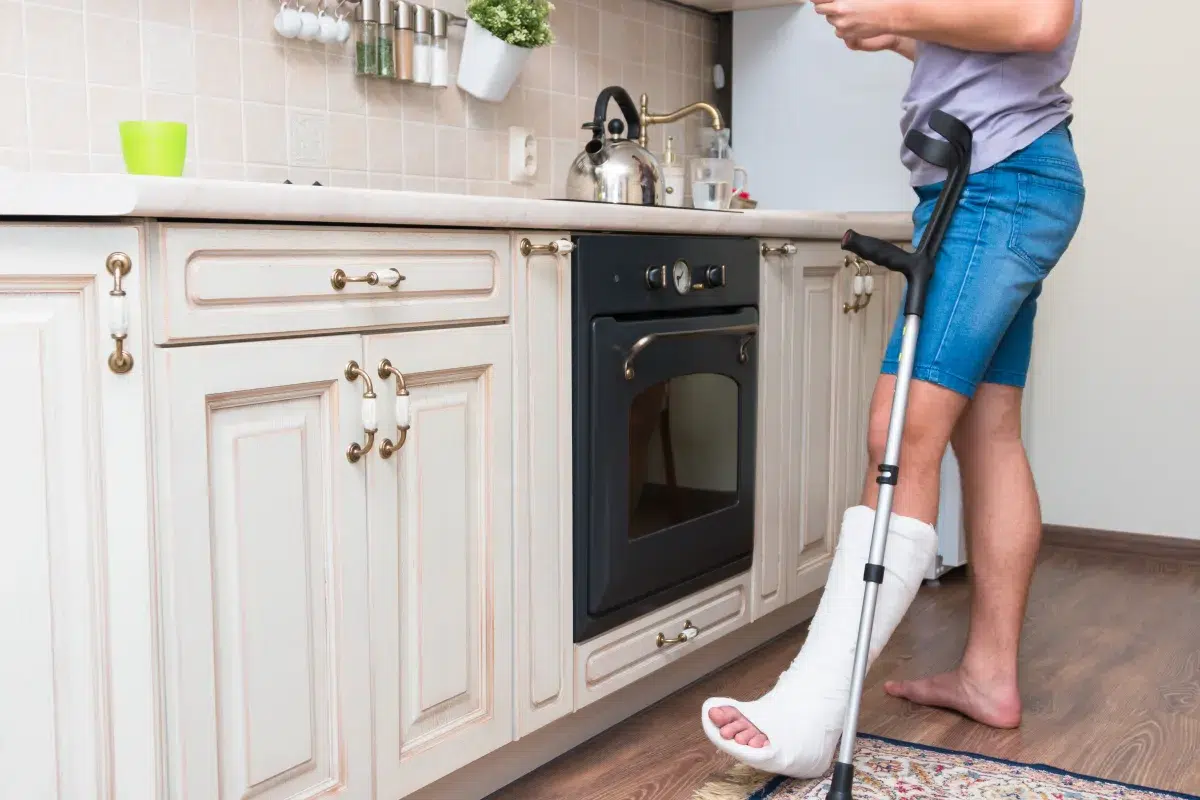 Person using crutches at home with a leg injury, representing car accident injury, delayed pain after a car accident, and life after car accident recovery.