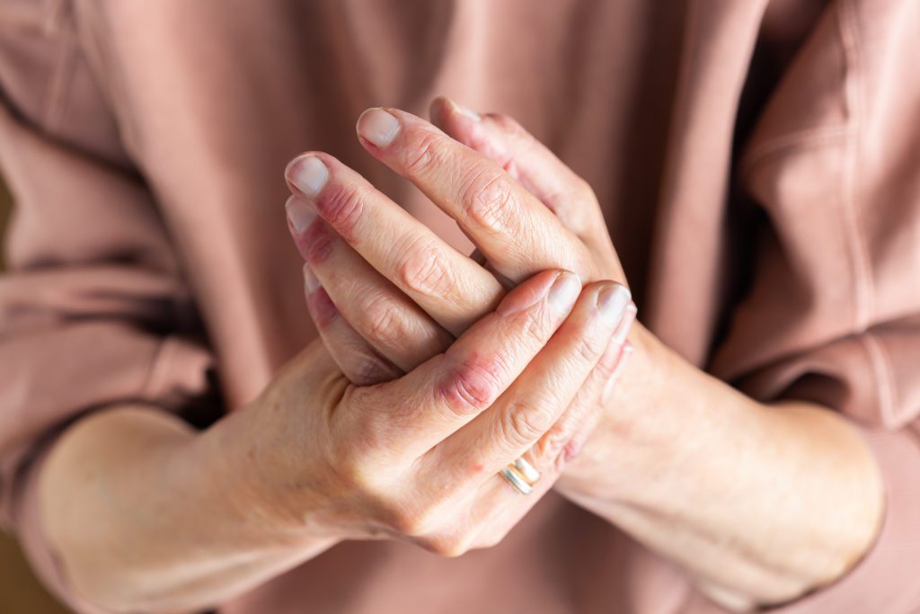 Elderly woman holding her arthritis hand from pain