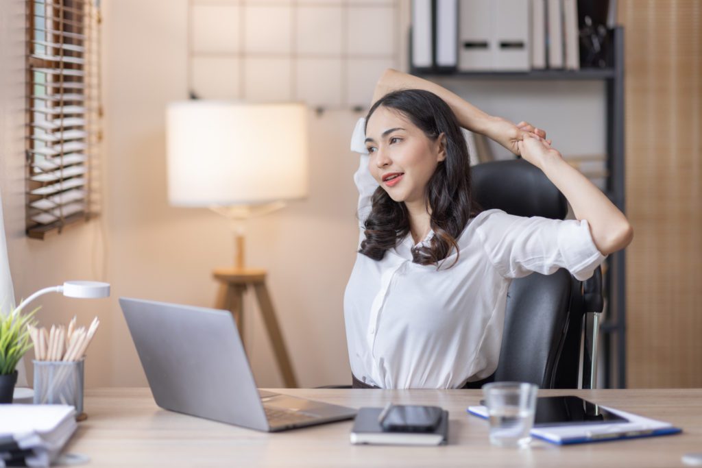 woman stretching arms and neck in a chair