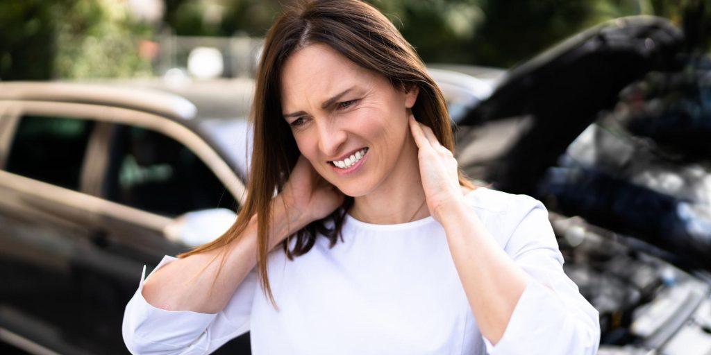 Woman in a white shirt with neck pain from a car accident